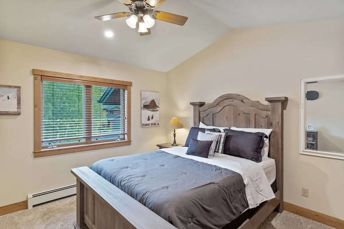 An inviting bedroom scene featuring a cozy bed near a window, a reading lamp, and tasteful wall art. The setting exudes comfort, with abundant sunlight and a calm, restful mood ideal for unwinding between work sessions.