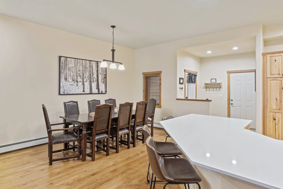 The image features a dining table set beneath a stylish chandelier, surrounded by wooden cabinetry and highlighted by framed artwork. The proximity to the kitchen is apparent, suggesting a seamless transition from cooking to dining and making it easy to host meals or enjoy casual gatherings.