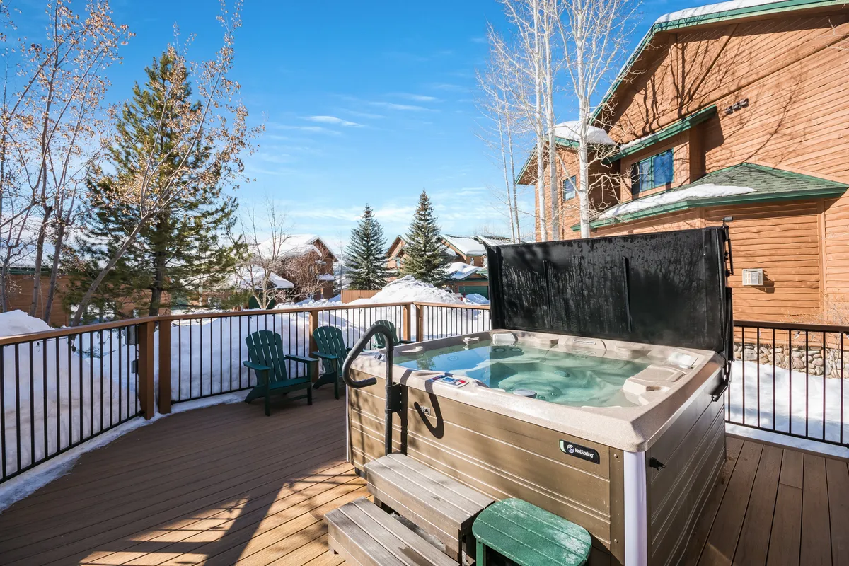 This exterior shot centers on a community hot tub on a deck, surrounded by seating and a snow-covered landscape. The tranquil winter setting suggests relaxation and indulgence after a day on the slopes, with space to socialize or stargaze against the serene backdrop.