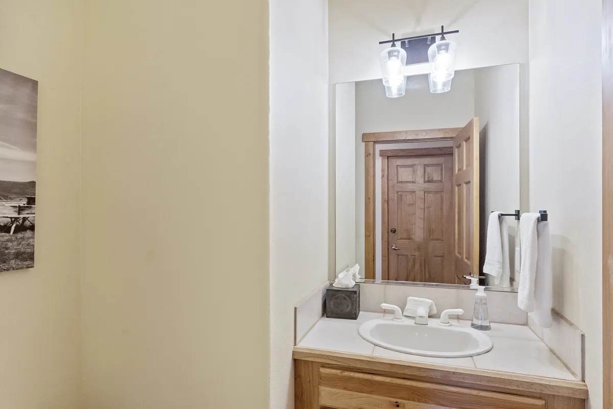 A compact, tastefully designed half bath featuring a modern sink, elegant mirror, and soothing light fixture. The space offers guests a convenient spot for quick refreshment and adds a touch of comfort to the main level.